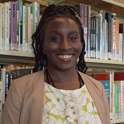 smiling person in front of book shelves