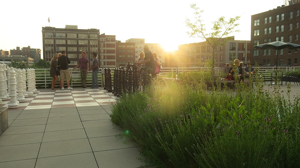 rooftop with groups of people and giant chess pieces