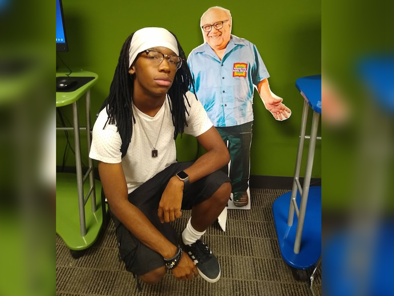 teenager squats next to Danny DeVito cutout