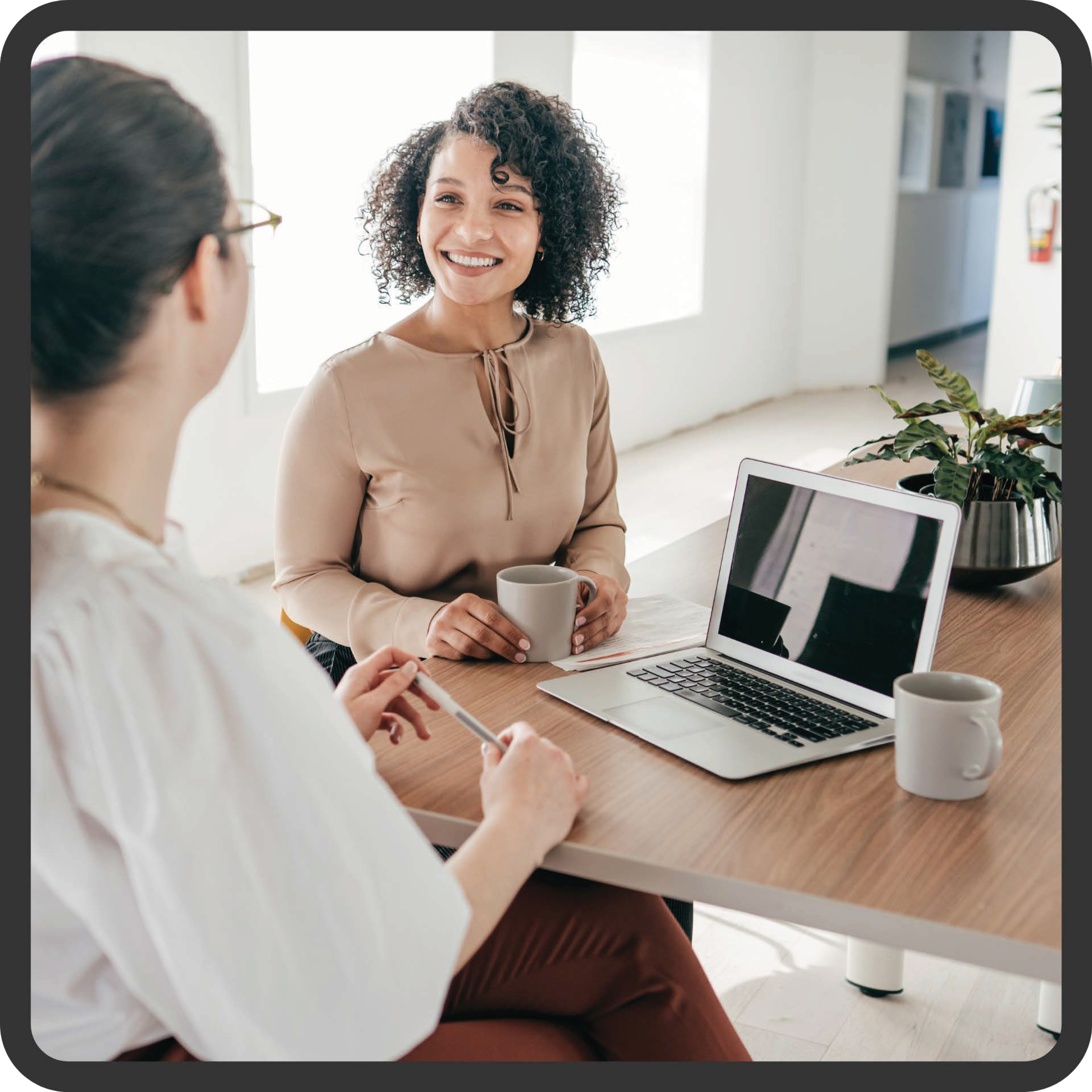 two women at table with laptop and mugs