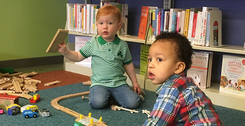 two kids play with books and train set
