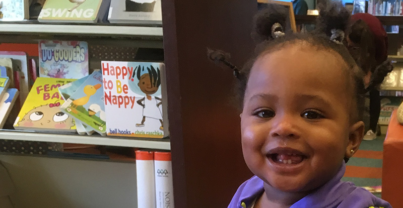 child smiling in front of book shelf