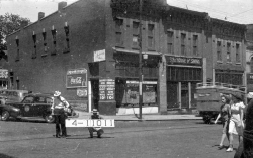 This 1940 photo displays a two-story brick building with storefronts, including The House of Swing.