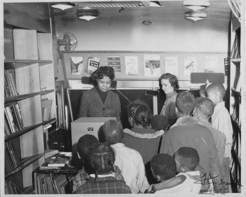 Children and librarians inside an old bookmobile