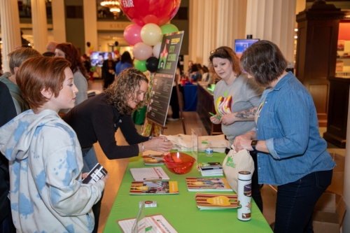 A parent and child stop at a table at the City School Fair at the Central Library.