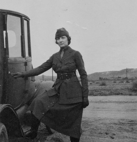 Black and white photo of a woman in uniform standing outside a vehicle.