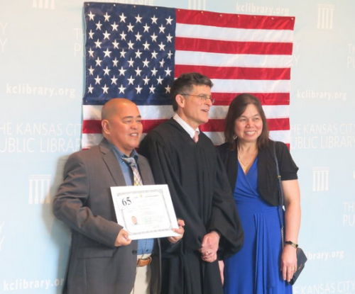 A new citizen stands next to a judge, flanked by an American flag, after a naturalization ceremony at the Library.