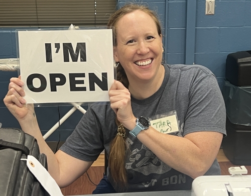 A volunteer at a Repair Cafe holds up a sign that says, "I'm open."