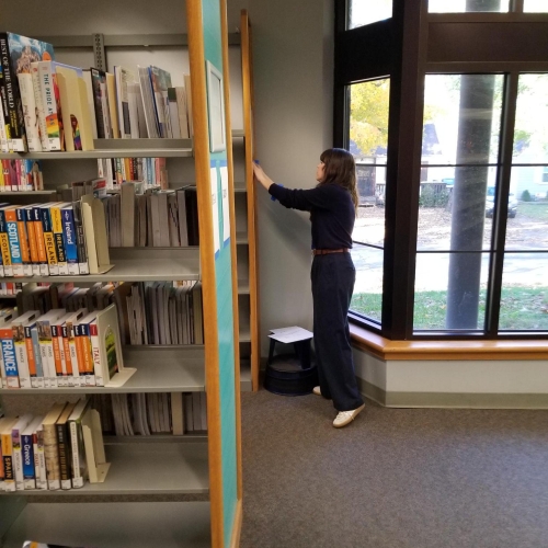 A woman stands next to shelving at the Waldo Branch.