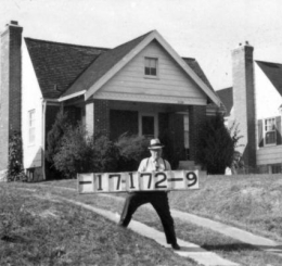 A man wearing a hat holds a signboard during the 1940 Jackson County tax assessment.