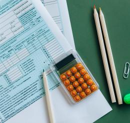 calculator and pencils on green desk with papers