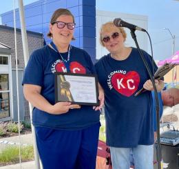 photo of two women in "KC" t-shirts holding a certificate