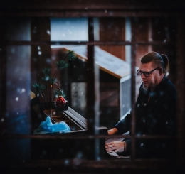 looking through snowy window at man playing piano