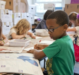 children writing on desks in row
