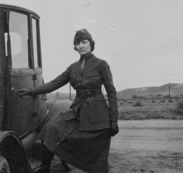 Black and white photo of a woman in uniform standing outside a vehicle.