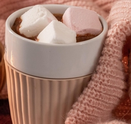 hot chocolate in blanket next to candle and marshmallows