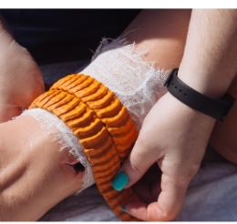 Close up of hands applying a bandage to a wounded arm