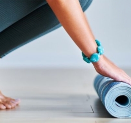 woman crouching rolling up yoga mat