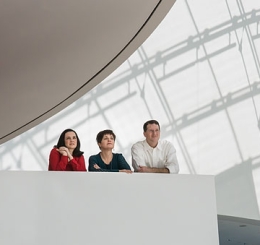 three people lean against balcony