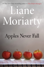 The cover of Apples Never Fall has a grey, smoky background with 4 apples on a table at the bottom of the cover