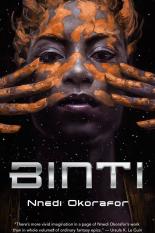 The cover of Binti shows a young, black woman with either orange paint or clay over her hands that have been run over her face and hair
