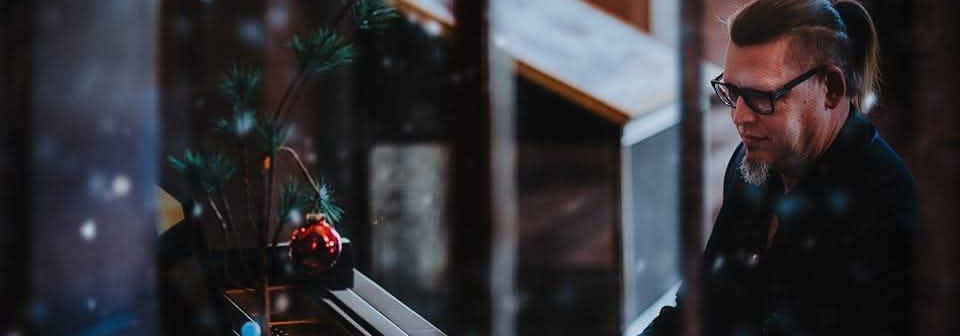 looking through snowy window at man playing piano