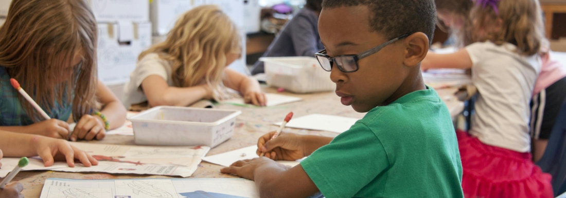 children writing on desks in row