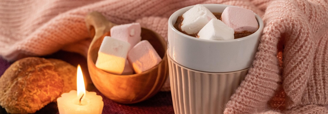 hot chocolate in blanket next to candle and marshmallows