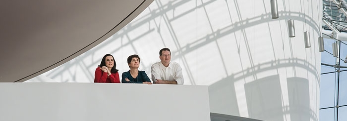 three people lean against balcony