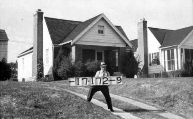 A man wearing a hat holds a signboard during the 1940 Jackson County tax assessment.