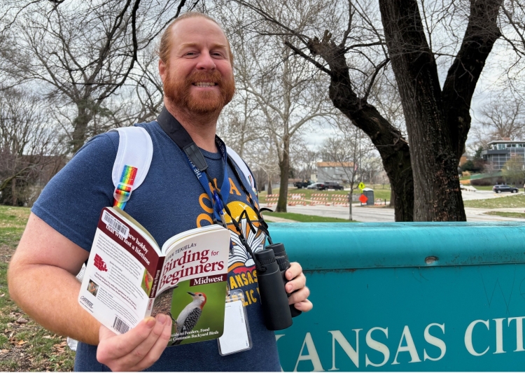 Ruiz Branch Manager Jimmy Thomas models a birdwatching kit near the branch sign.