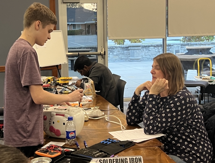 A volunteer fixes an item at a Repair Cafe. 