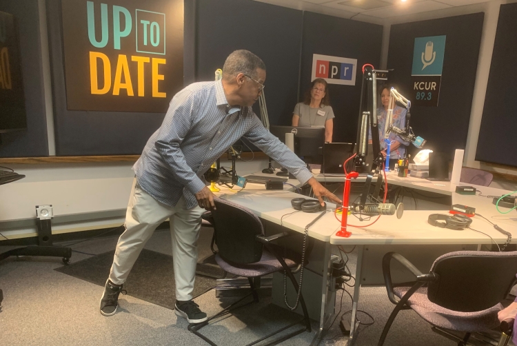 Three people in a newsroom.