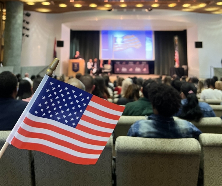 An American flag in the foreground of a naturalization ceremony at the Library.
