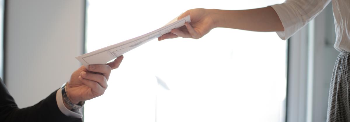 person handing paper to another