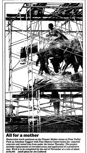 Newspaper scan showing a photograph of a statue under construction with scaffolding around it