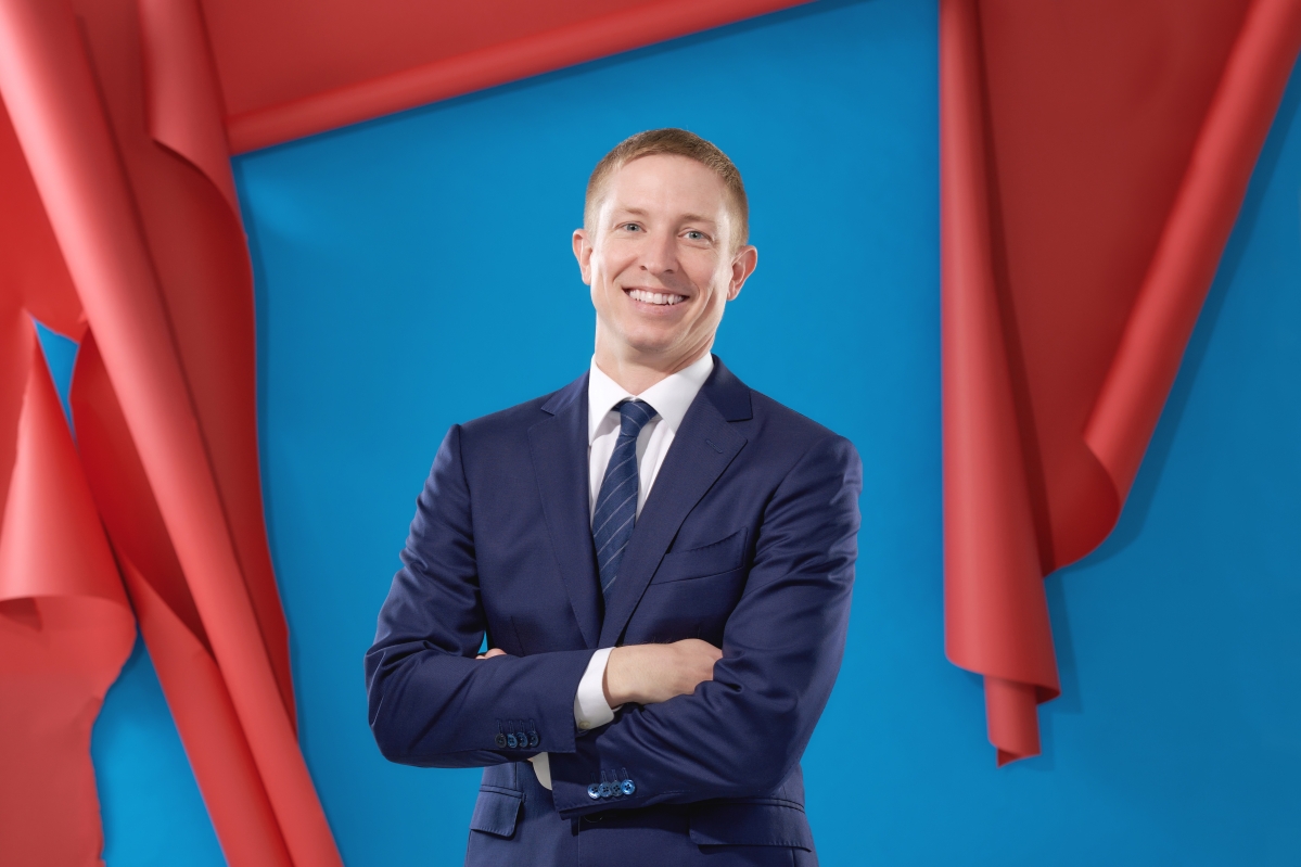 man smiles in front of coiled red paper