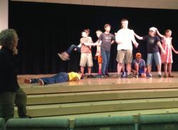 Director, at left, and a group of kids on stage. 