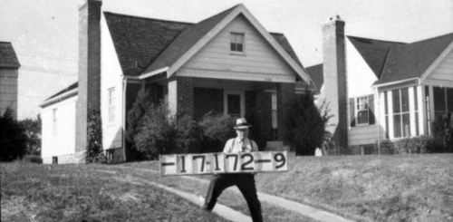 A man wearing a hat holds a signboard during the 1940 Jackson County tax assessment.