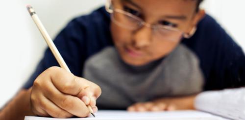 Boy holding a pencil doing homework