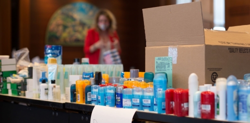 Volunteers sort hygiene products in meeting room.