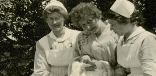 Three nurses holding an infant