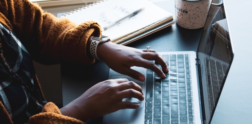 A woman's hands typing on a laptop keyboard.