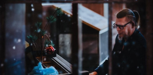 looking through snowy window at man playing piano
