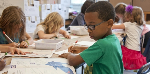 children writing on desks in row