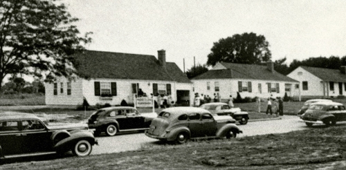 black and white photo of houses on street with cars parked