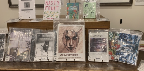 Photo shows several zines displayed on a table.