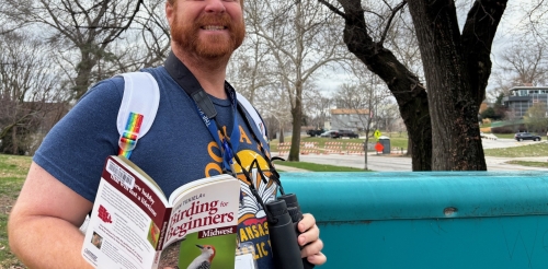 Ruiz Branch Manager Jimmy Thomas models a birdwatching kit near the branch sign.