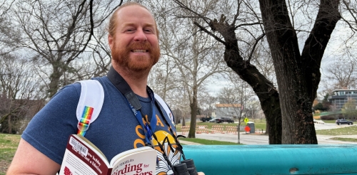 Ruiz Branch Manager Jimmy Thomas models a birdwatching kit near the branch sign.
