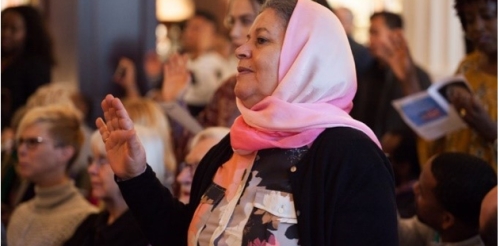 A woman raised her hand during a naturalization ceremony at the Library.